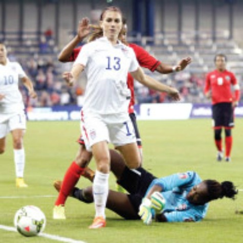 BLOCKED: Trinidad and Tobago goalkeeper Kimika Forbes, bottom, knocks the ball away as United States Alex Morgan (13) attempts to score during the first half of their CONCACAF Women’s Championship match on Wednesday in Kansas City, USA. —Photo: AP